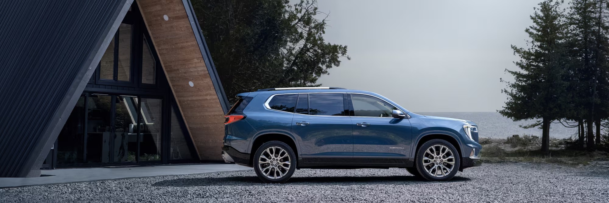 Side view of the 2025 GMC Acadia parked outside a house.